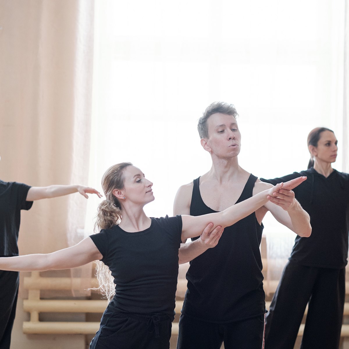 card-adult-dance-class-nrsb Adult dancers dressed in black practising in a sunlit studio, one dancer guiding another’s arm position